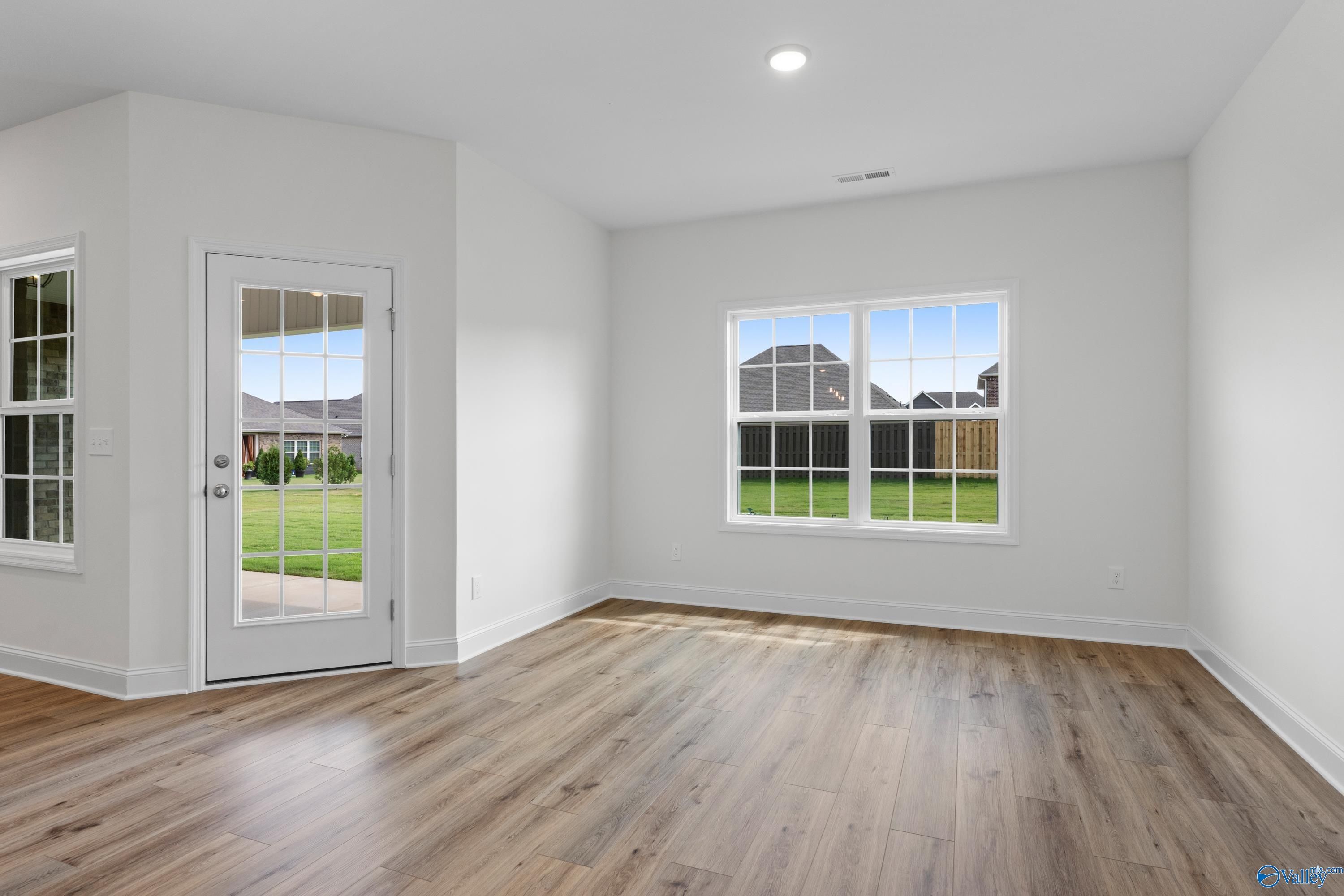 Bright bonus room with hardwood floors, large windows, and French doors to lush backyard in Davidson Homes The Rockford B, Toney, AL