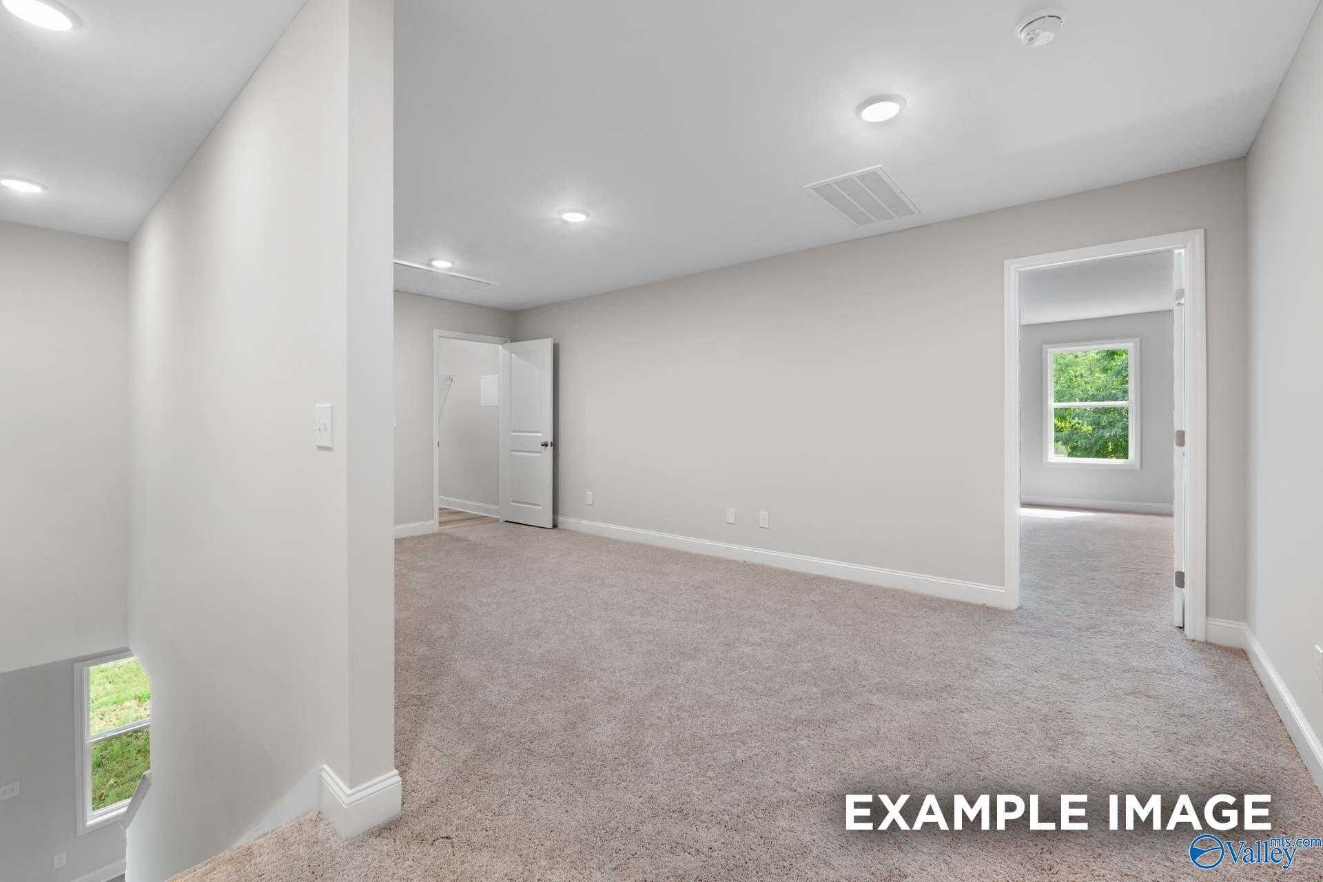 Carpeted upstairs hallway with recessed lights and open bedroom door in The Camden 3-bedroom home by Davidson Homes, Huntsville AL