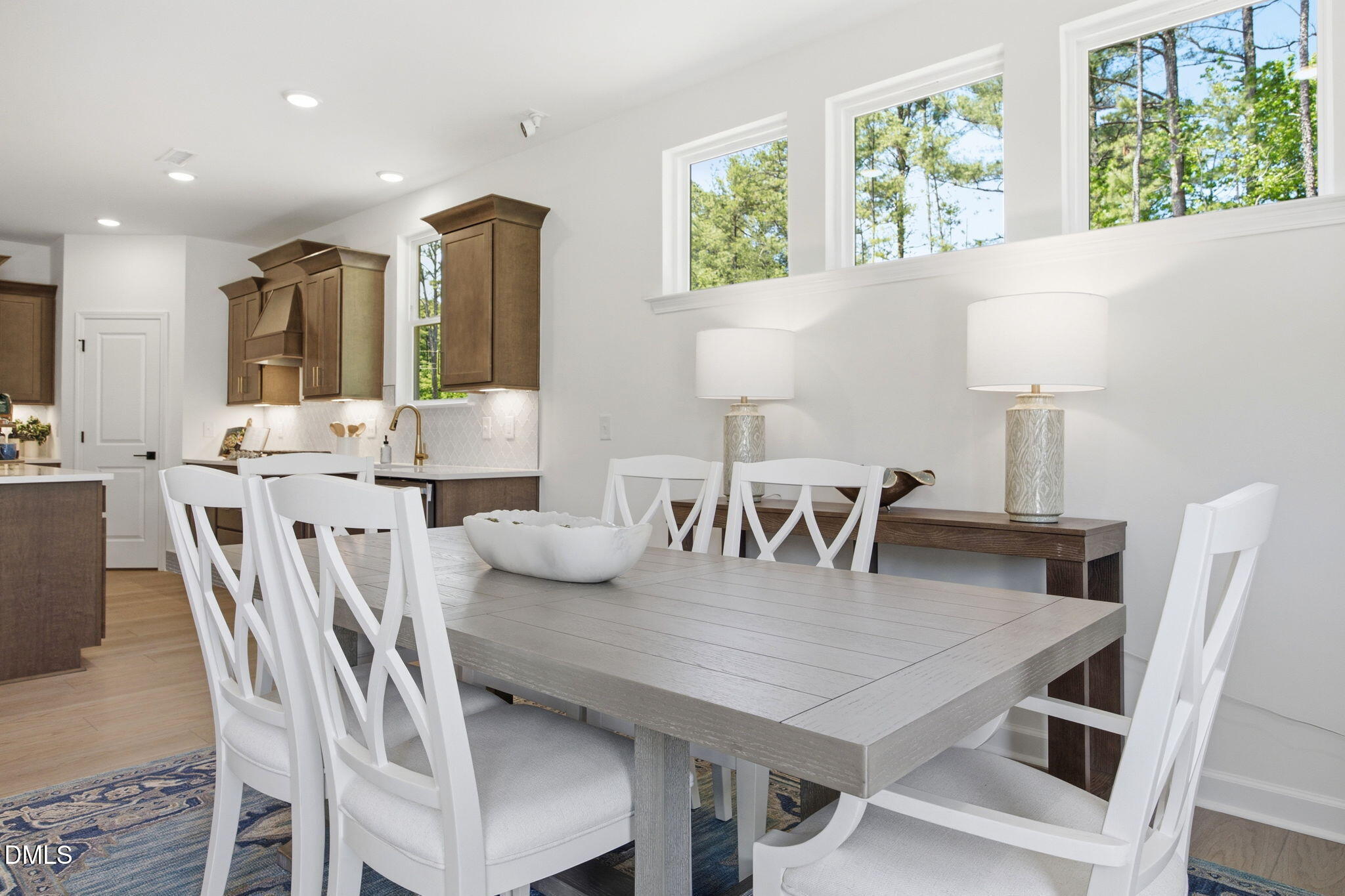 Bright dining area with white chairs and gray table in The Ashport M floor plan at Wendell Ridge, Wendell, North Carolina.