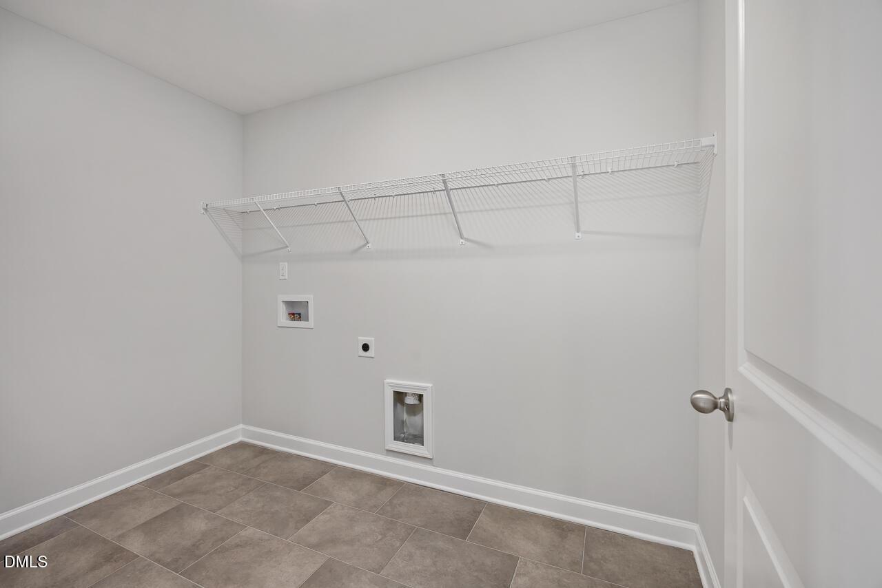 Modern laundry room featuring wire shelving, washer/dryer hookups in 5-bed Davidson Homes The Willow G, Angier, NC