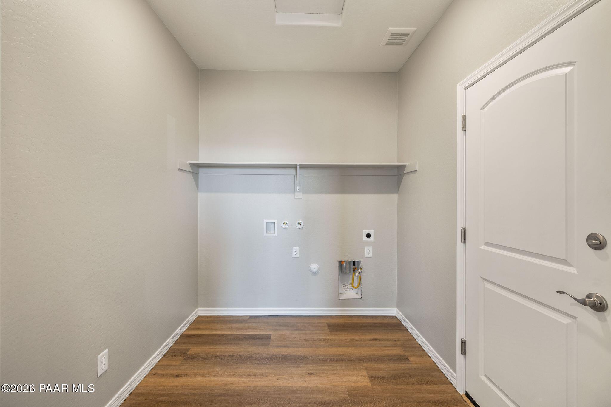 Spacious laundry room with built-in shelving, washer dryer hookups, and laminate wood flooring in Davidson Homes The Frontier A, Prescott Valley, Arizona