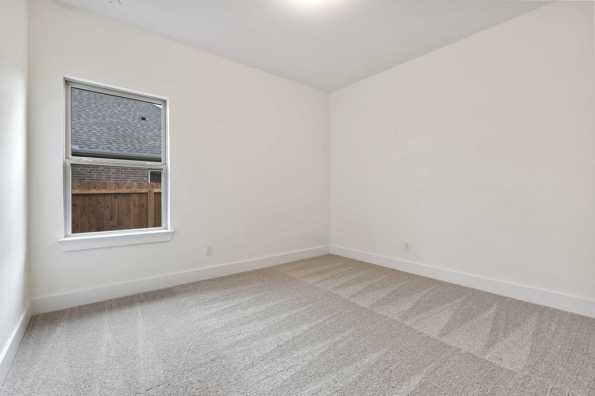 Bright secondary bedroom with neutral walls, carpet flooring, and window view in Davidson Homes The Rockford C, Josephine, Texas
