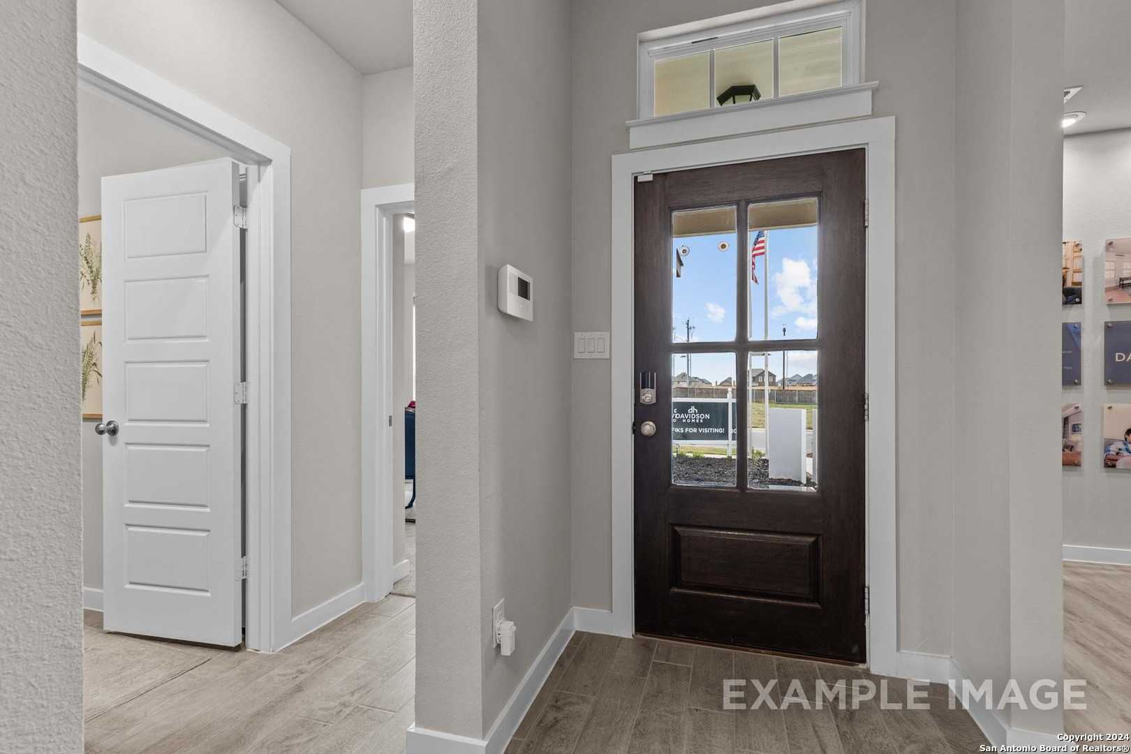 Welcoming foyer with dark wood front door, transom window, and American flag view in The Collin A 3-bedroom home, Seguin, Texas