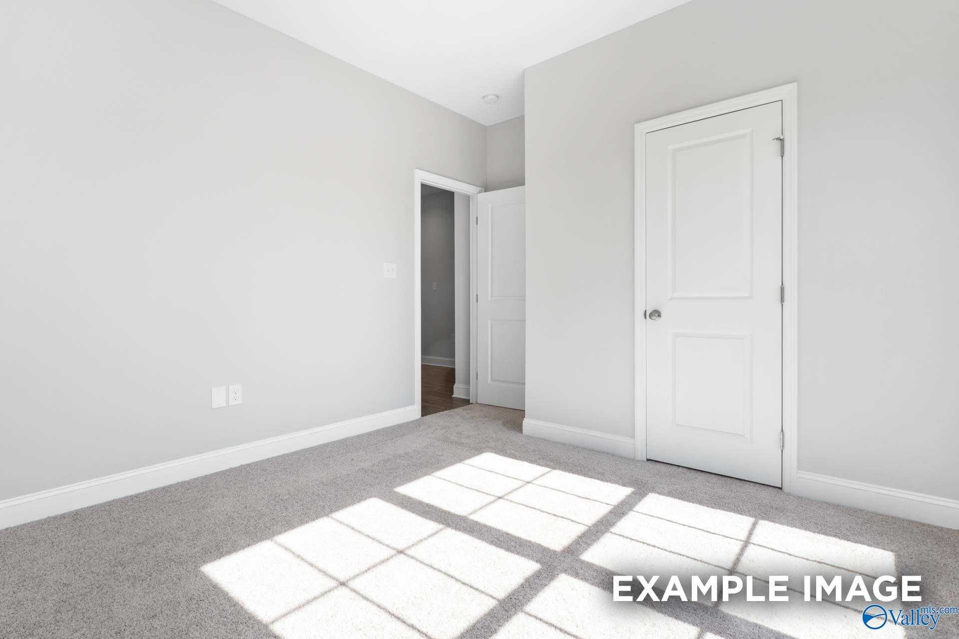Sunlit bedroom with light gray walls, white doors, and carpeted floor in Davidson Homes The Franklin C, Meridianville, Alabama