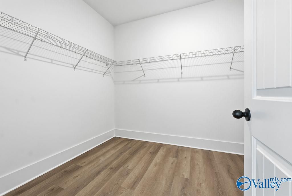 Spacious walk-in closet with wire shelving, white walls, and hardwood flooring in Davidson Homes The Rockford, Hartselle, Alabama