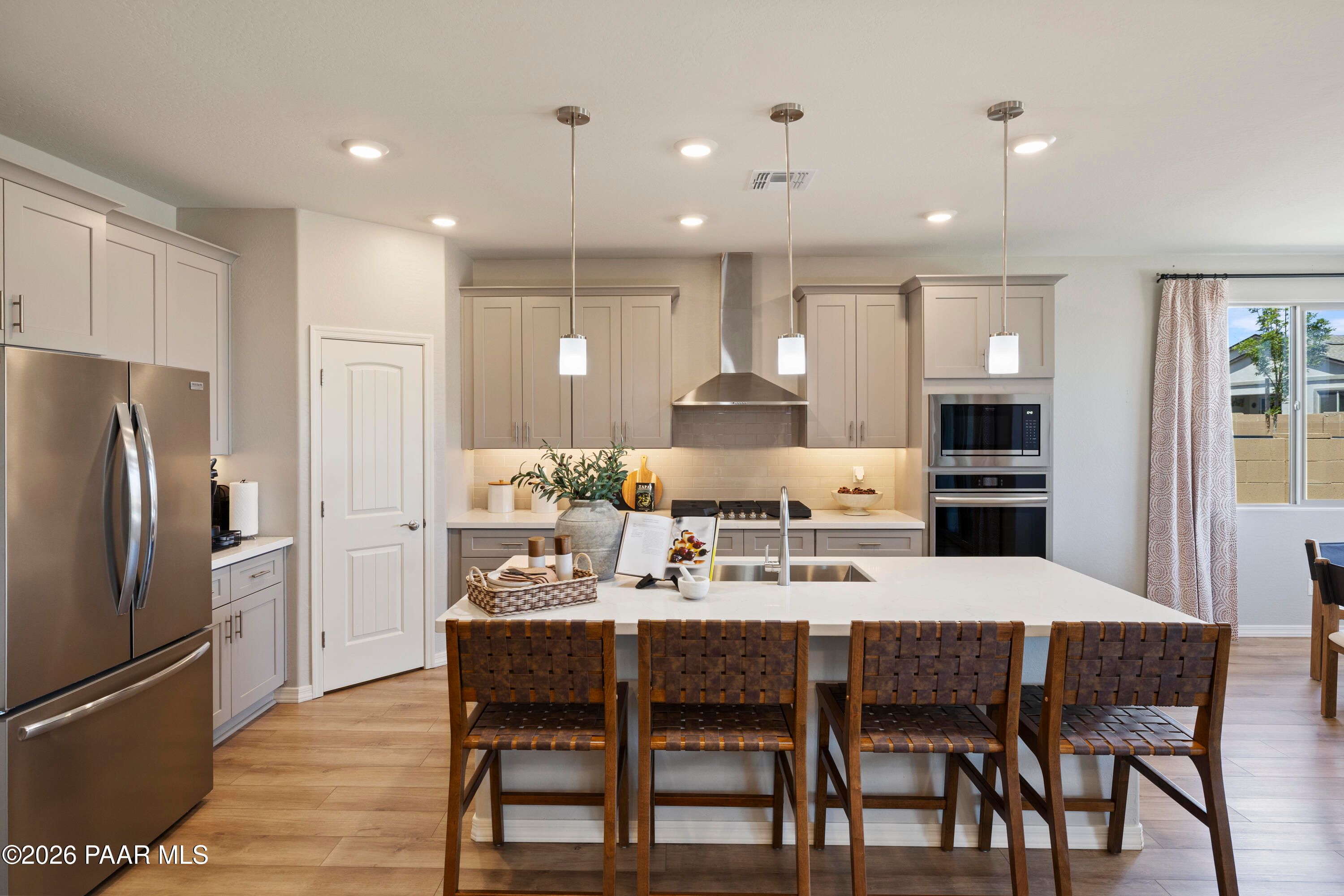Modern kitchen with large island, stainless appliances, and pendant lighting in Harmony A home at Pronghorn Ranch, Prescott.