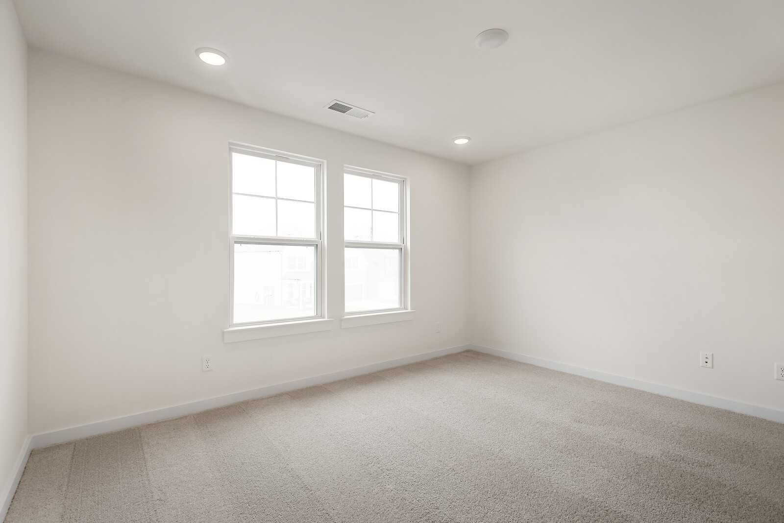 Bright secondary bedroom with neutral walls, large windows, and carpet flooring in Davidson Homes The Logan C, Gallatin, TN