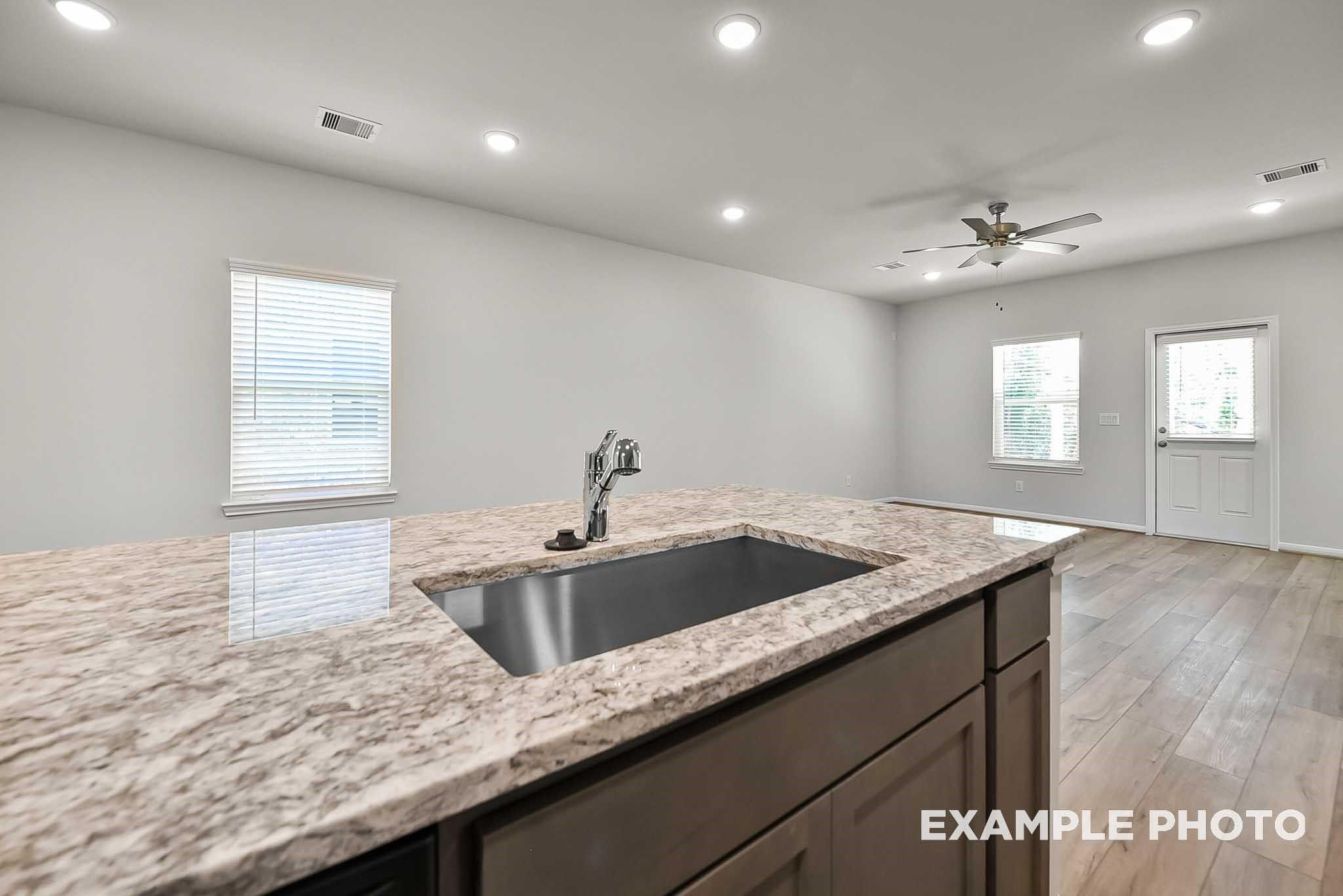 Modern kitchen island with granite countertops and stainless sink in The Blanco F floor plan, Spring Branch Crossing, Conroe.