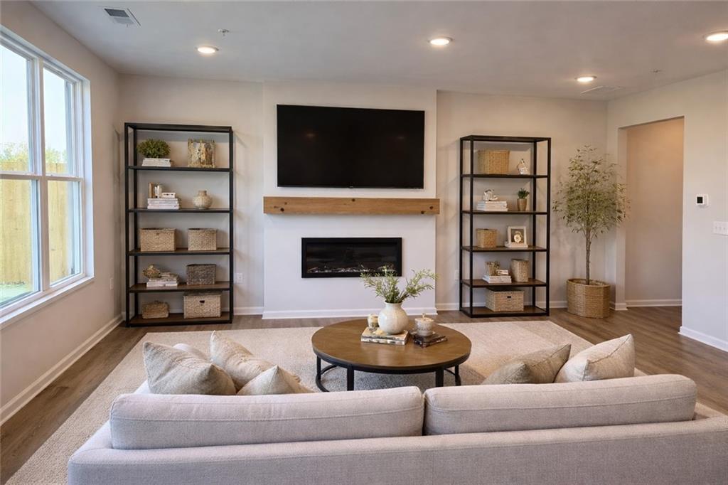 Cozy living room featuring fireplace, mounted TV, flanking bookshelves, beige sofa in Davidson Homes The Wake E, Cumming GA
