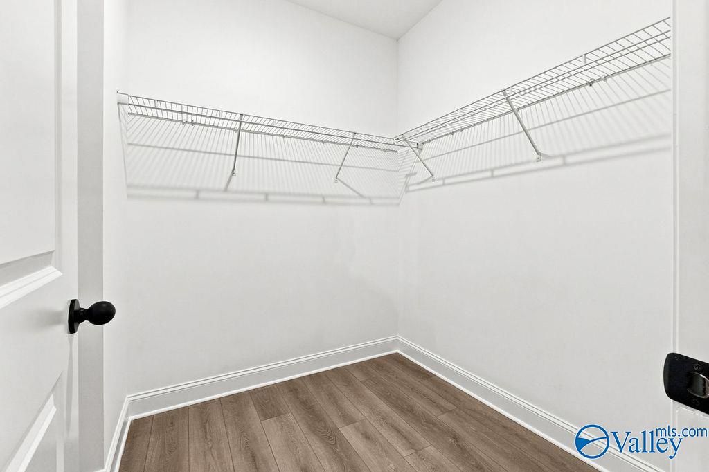 Walk-in closet with white wire shelving and wood-look flooring in The Camilla C floor plan at The Retreat at Cain Park.