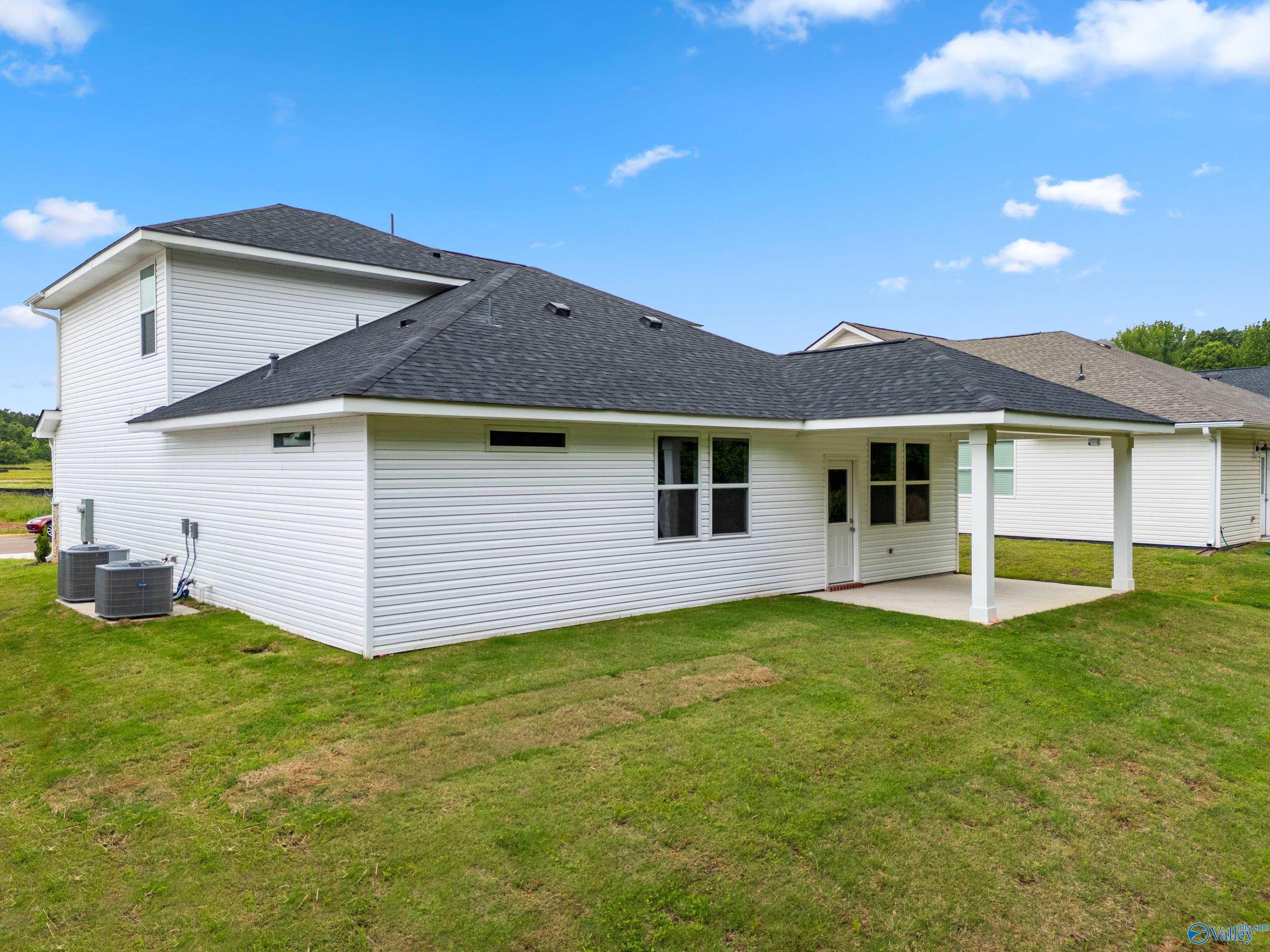 Rear view of Davidson Homes The Stella two-story home with covered patio and grassy backyard in Forest Glen, Hazel Green, Alabama