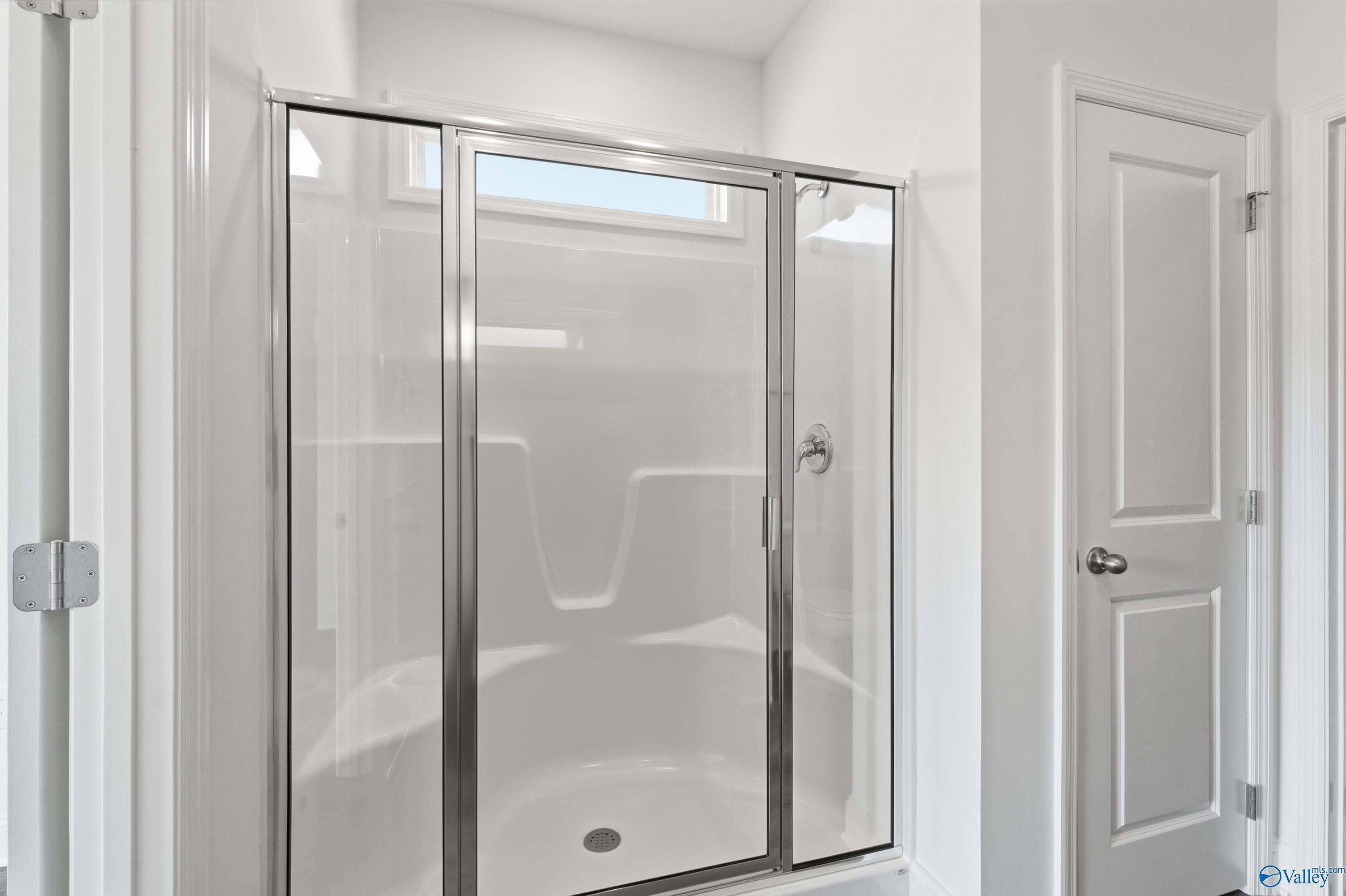 Modern glass shower enclosure with white tile surround and transom window in The Asheville master bath, Davidson Homes, Huntsville AL