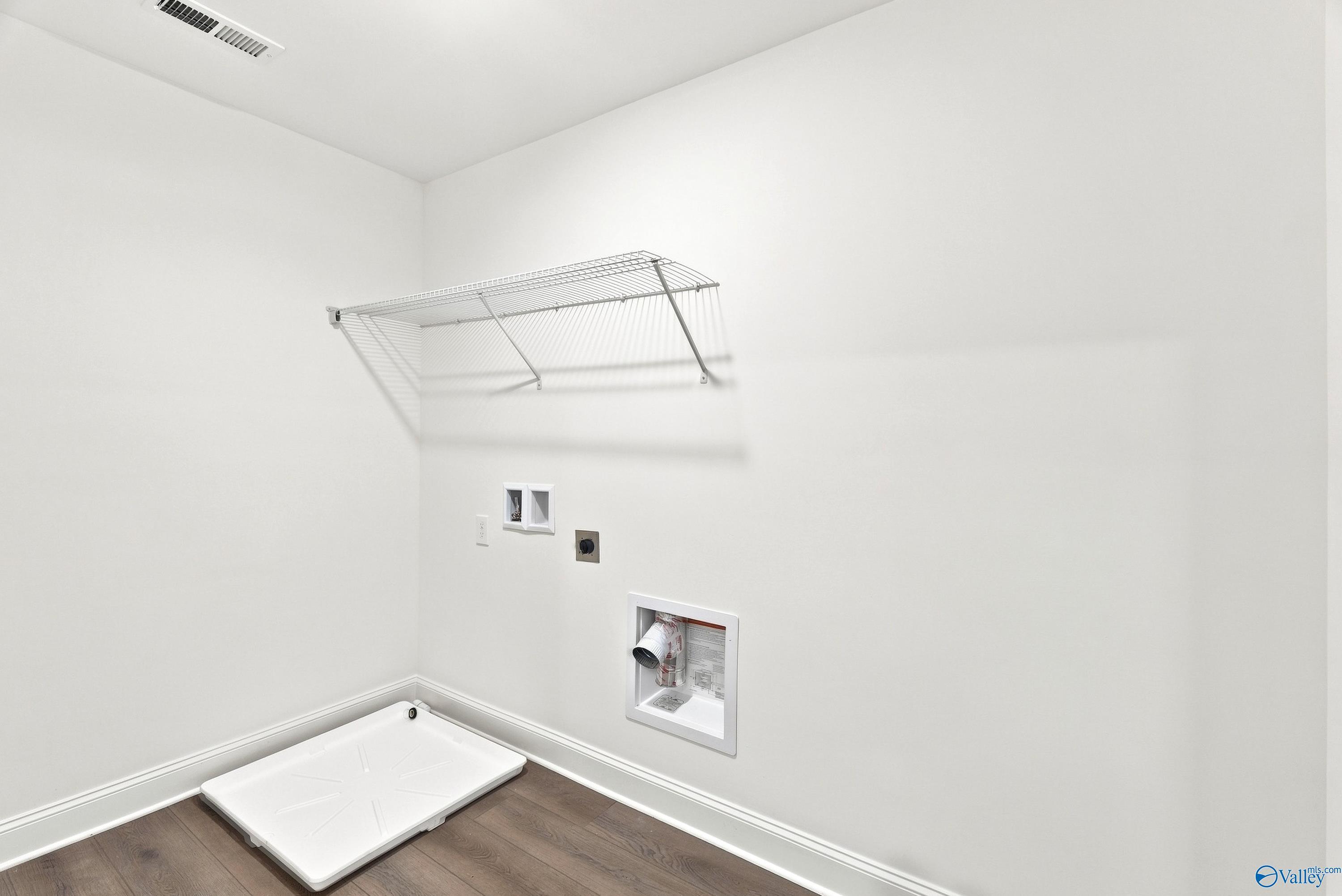 Laundry room with wire shelving and floor drain in The Shelby B floor plan at Jaguar Hills, Huntsville, Alabama.