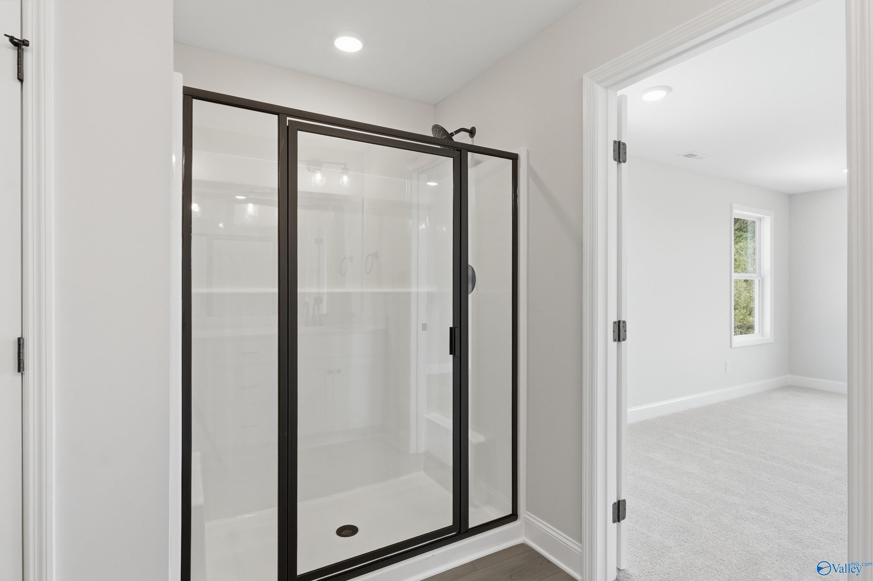 Modern walk-in shower with black-framed glass enclosure in master bath of The Chelsea D by Davidson Homes, Cullman, AL