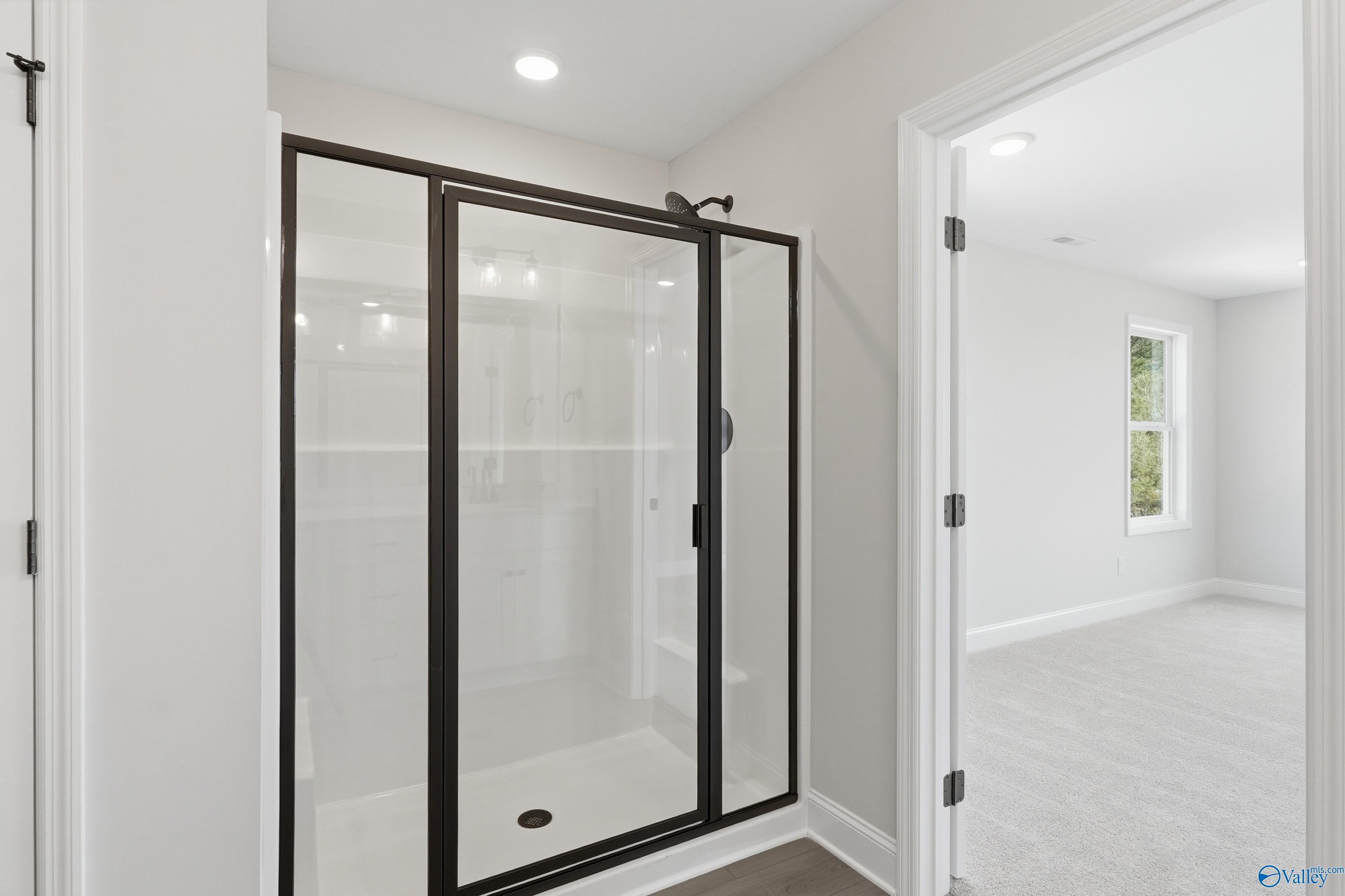 Modern walk-in shower with black-framed glass enclosure in master bath of The Chelsea D by Davidson Homes, Cullman, AL