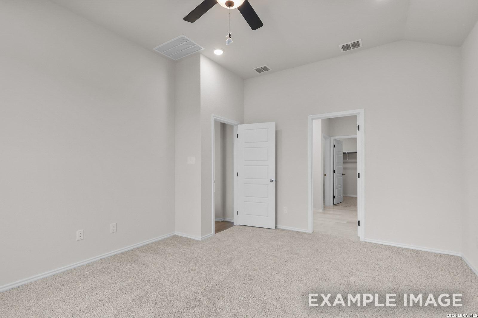 Spacious bedroom with vaulted ceilings, ceiling fan, and walk-in closet in The Sequoia C floor plan, Royal Crest, San Antonio.