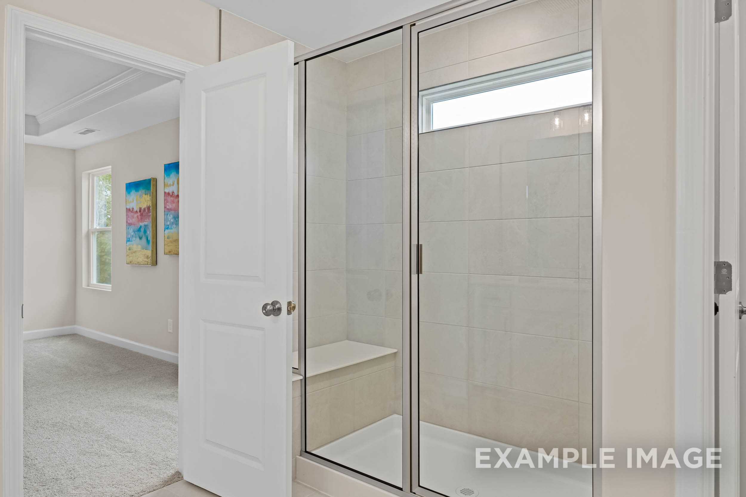 Spacious master bathroom in The Preston B featuring frameless glass shower, subway tile bench, and neutral tones