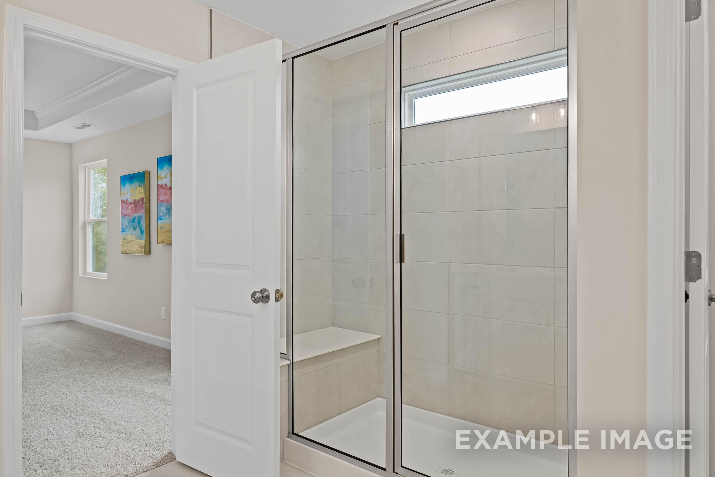 Spacious master bathroom in The Preston B featuring frameless glass shower, subway tile bench, and neutral tones
