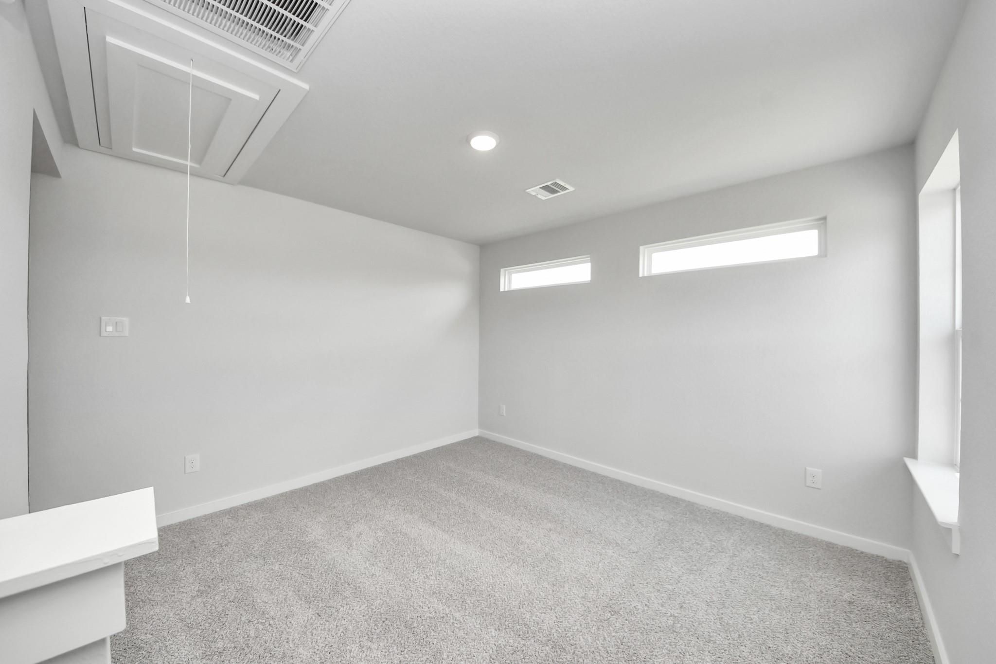 Bright bedroom with neutral walls and carpet in The Sabine F floor plan at Liberty Estates, Cleveland, Texas.