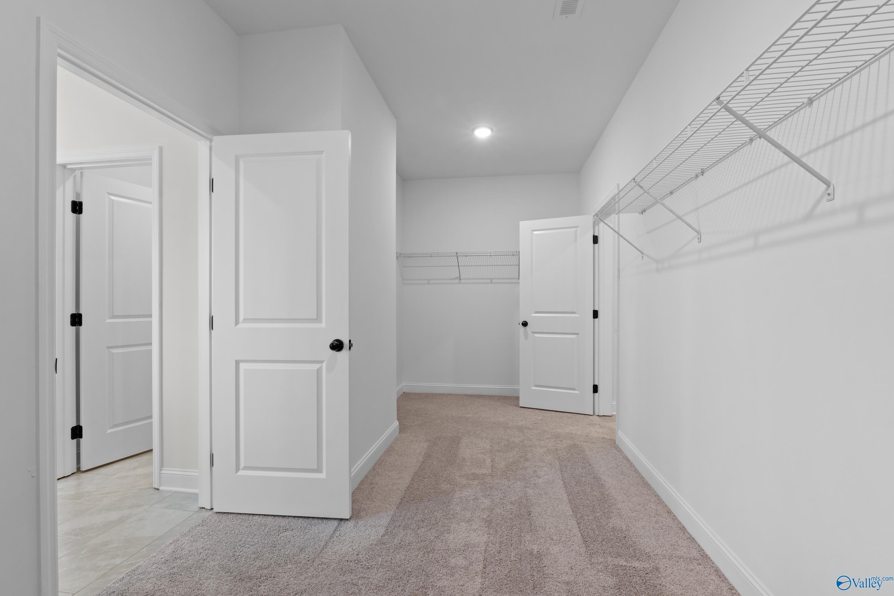 Spacious walk-in closet with wire shelving, hanging rods, and double doors in Davidson Homes The Rockford B, Toney, Alabama
