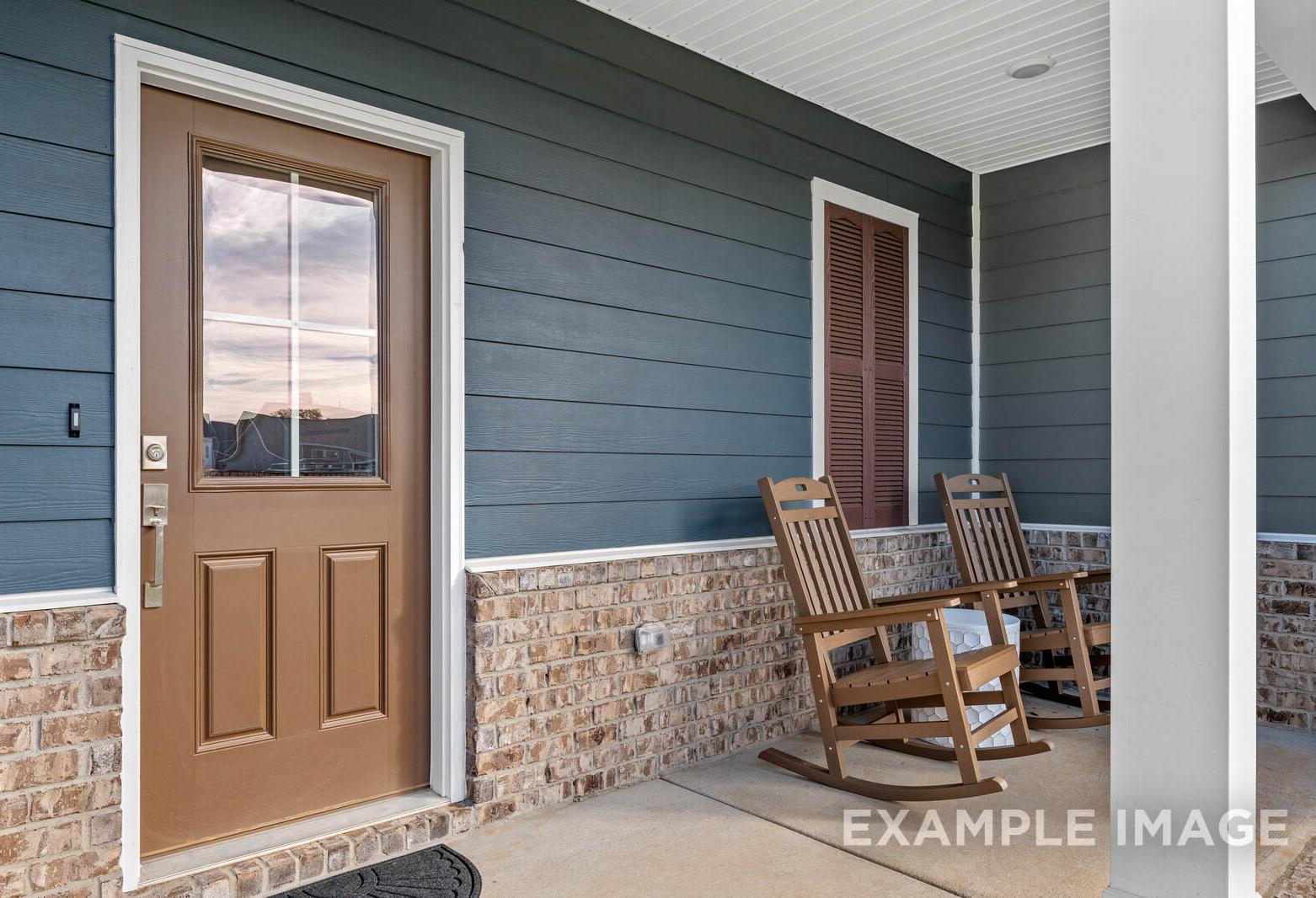 Charming front porch of The Gordon A home with blue siding, brick accents, glass-paneled door, and rocking chairs