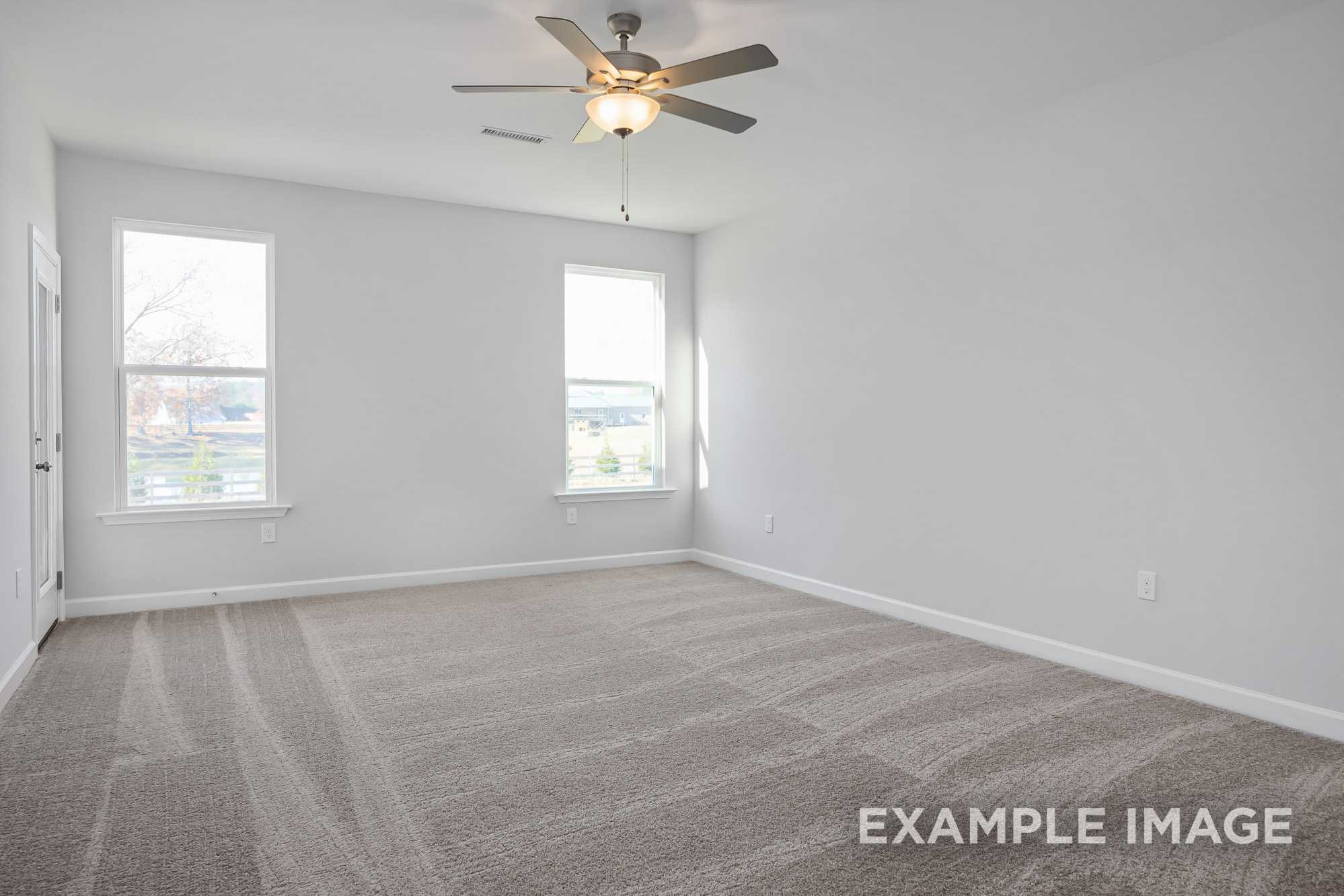 Spacious empty master bedroom in The Cypress D II with gray carpet, white walls, large windows, and ceiling fan