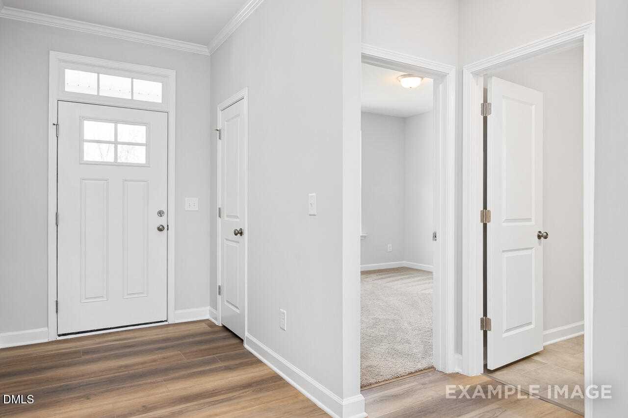 Bright entry foyer with white doors, luxury vinyl plank floors, and hallway in Davidson Homes The Daphne C, Lillington NC