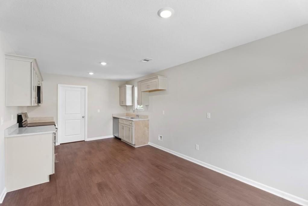 Modern kitchen with white shaker cabinets, stainless sink, hardwood floors, and gray walls in Davidson Homes The Washington, Phenix City, AL