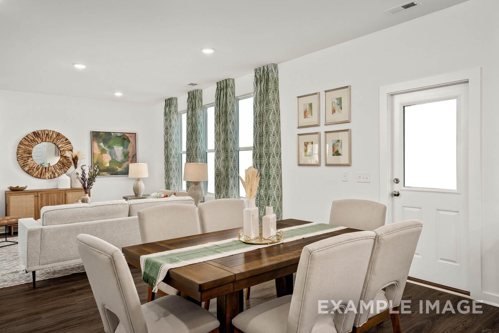 Spacious dining room in The Gordon C with wooden table, beige chairs, large windows, and abstract art