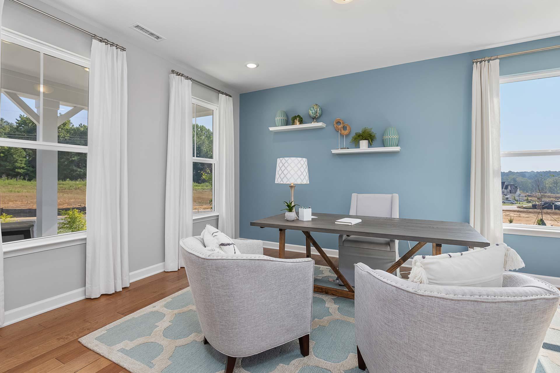 Cozy home office in Highland Forest, Fuquay-Varina NC with blue walls, wooden desk, gray armchairs, and scenic window views