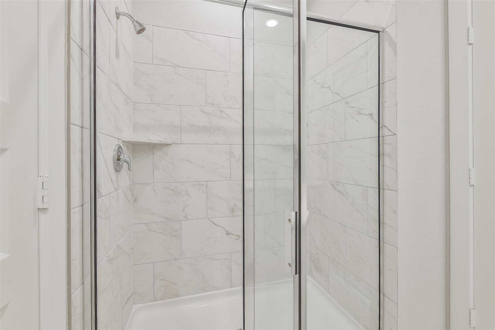 Frameless glass walk-in shower with subway tile walls and rain showerhead in master bath, Rio Grande H home, Magnolia TX