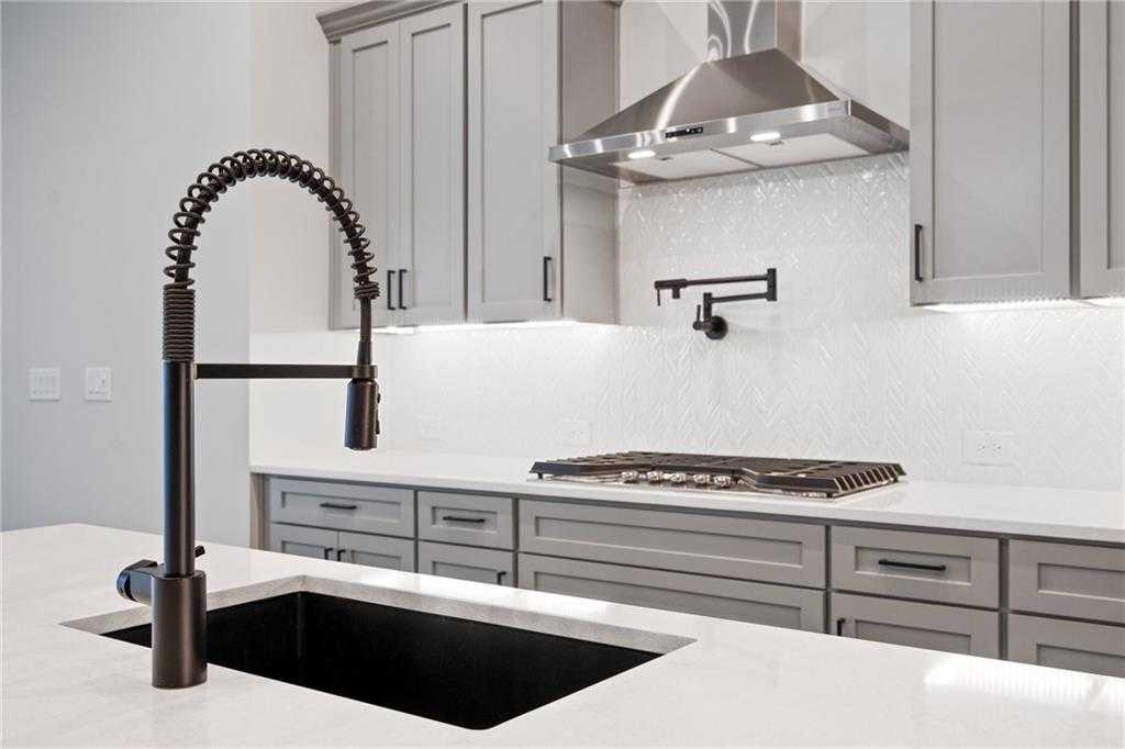 Modern kitchen with black farmhouse sink, bronze pull-down faucet, white quartz counters, gray shaker cabinets in Davidson Homes Seaside B, Woodstock GA