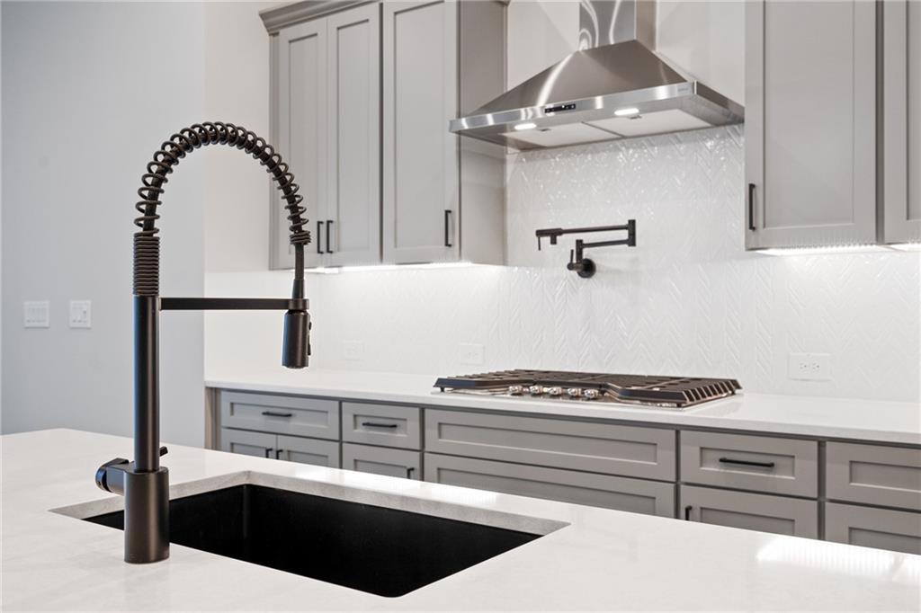 Modern kitchen with black farmhouse sink, bronze pull-down faucet, white quartz counters, gray shaker cabinets in Davidson Homes Seaside B, Woodstock GA
