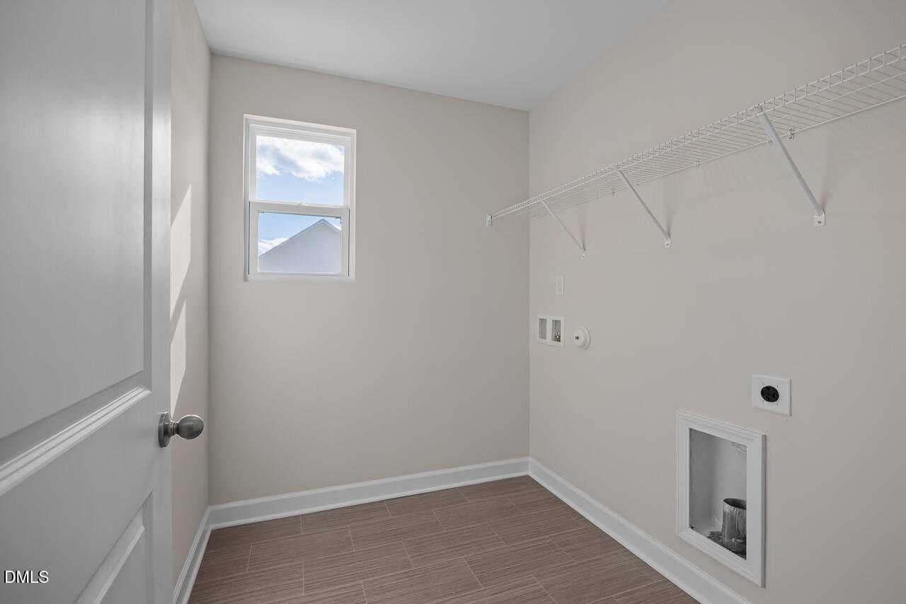 Bright laundry room with wire shelving, window overlooking yard, utility sink in Davidson Homes The Gavin C, Lillington, NC