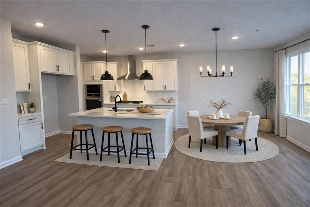Modern white kitchen island with sink, pendant lights, and round dining table in The Wake E floor plan, Cumming, Georgia