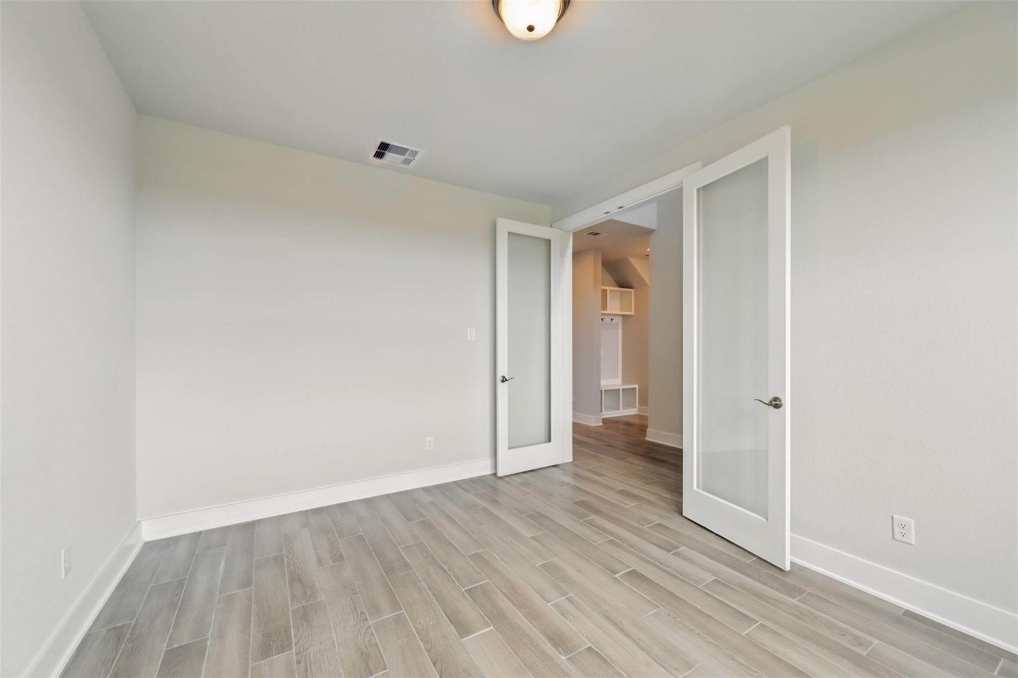 Bright bedroom with light wood floors, French doors to walk-in closet in Davidson Homes The Philip A, Lago Mar, Texas City