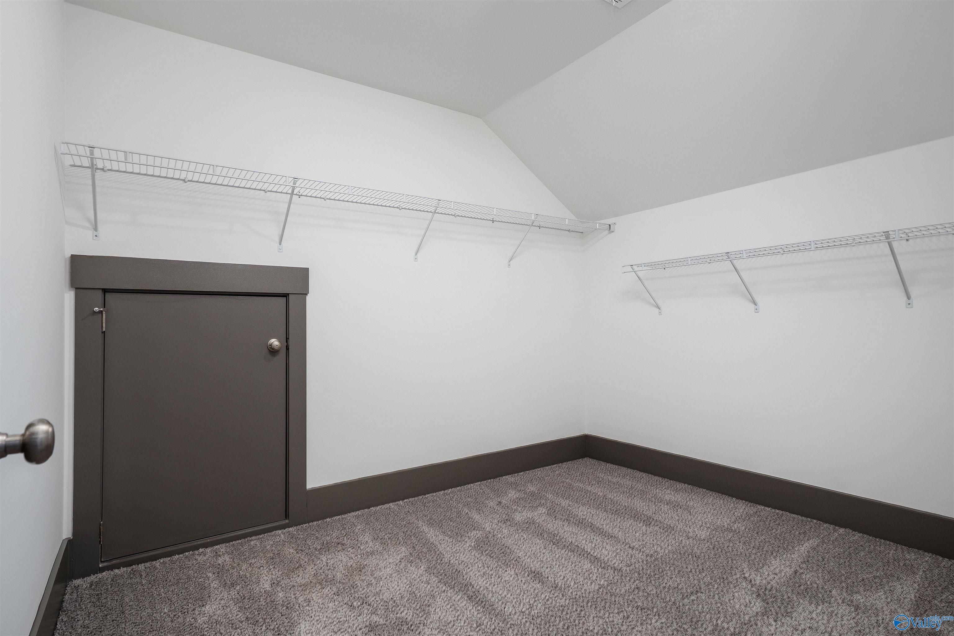 Spacious walk-in closet with wire shelving, sloped ceiling, and gray door in Davidson Homes The Rockford B, Madison, AL