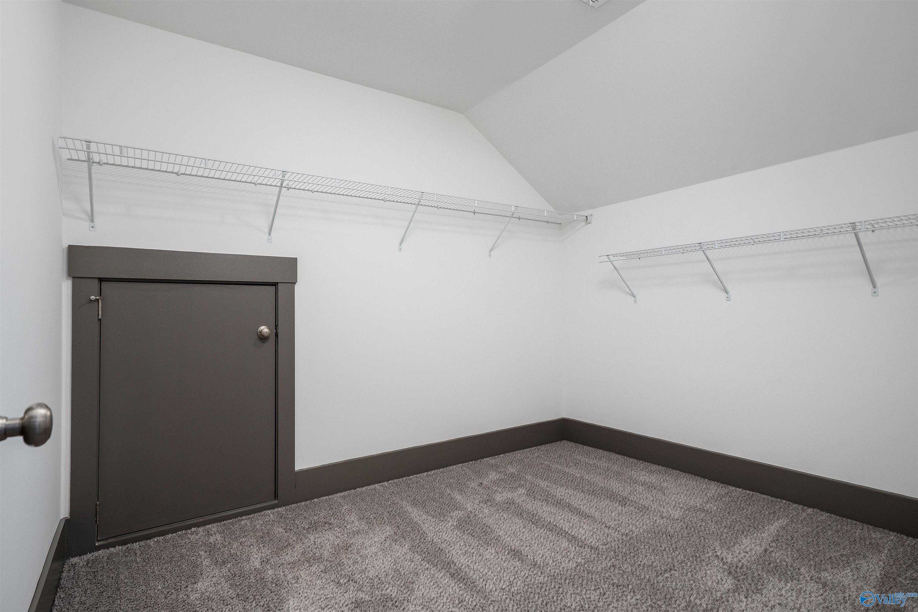 Spacious walk-in closet with wire shelving, sloped ceiling, and gray door in Davidson Homes The Rockford B, Madison, AL