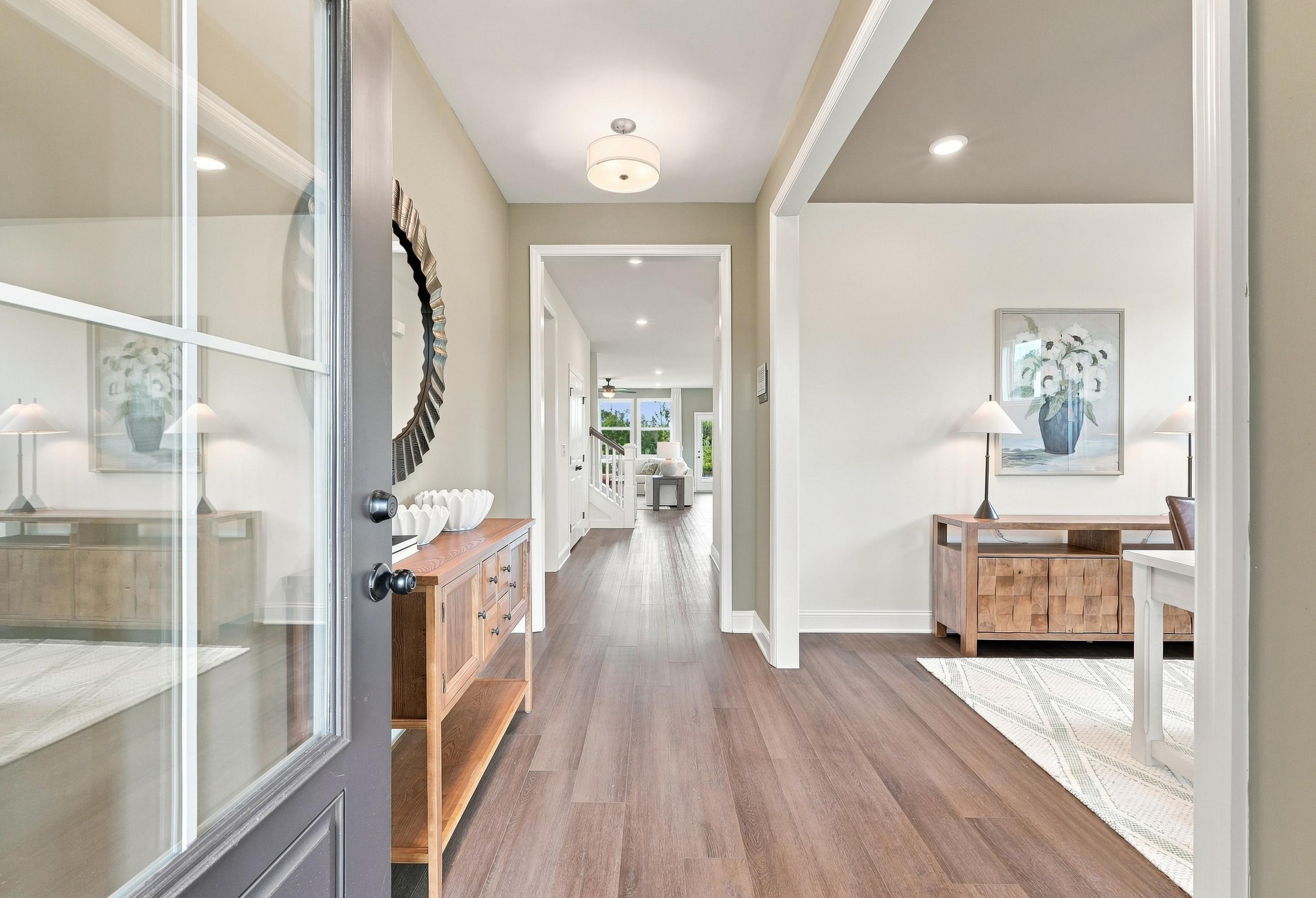 Bright foyer entrance of The Ashport featuring hardwood floors, modern decor, and a view into the open-concept living area.