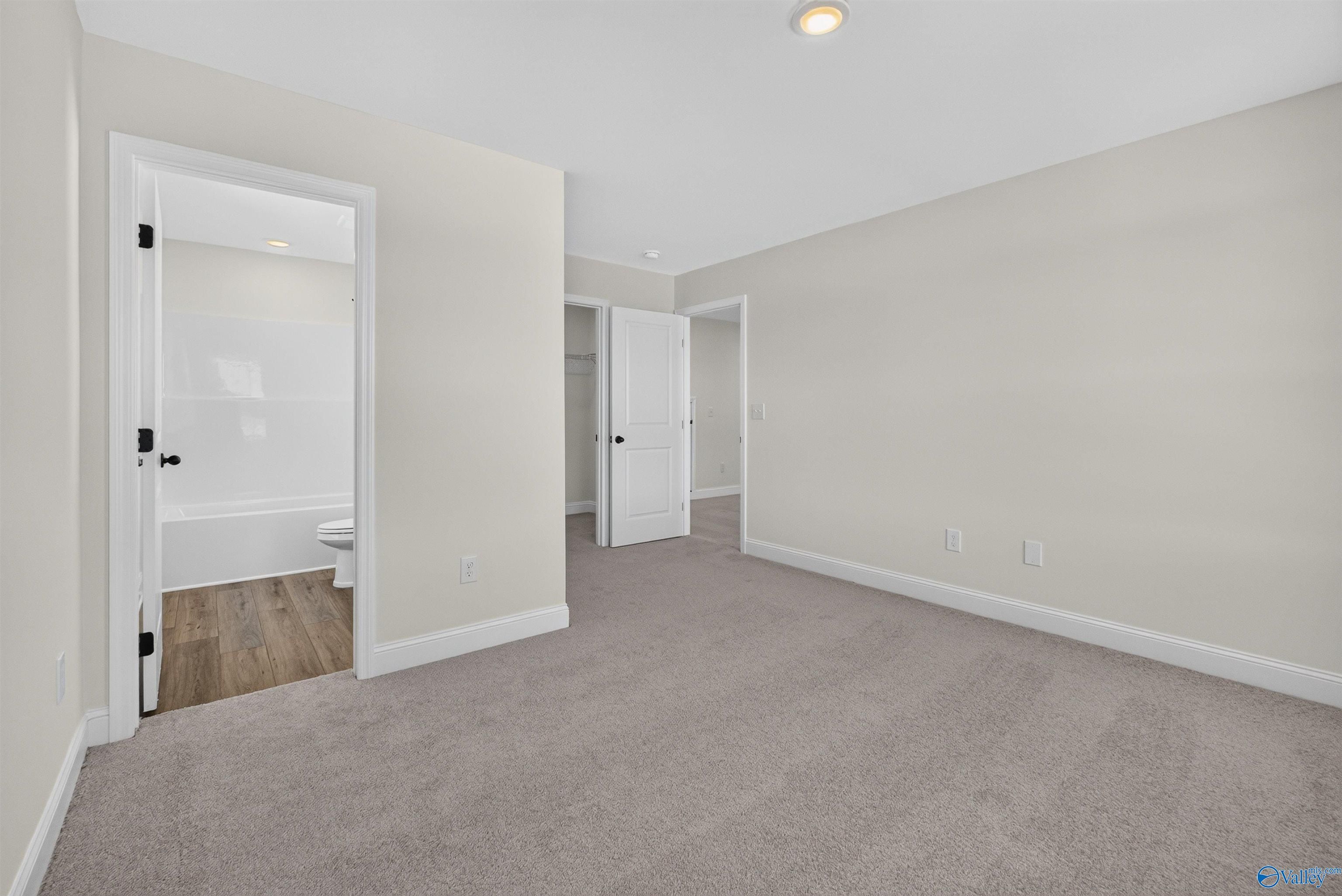 Spacious carpeted bedroom with en suite bath and walk-in closet in Davidson Homes Ashport L floor plan, Berry Cove, New Market, Alabama
