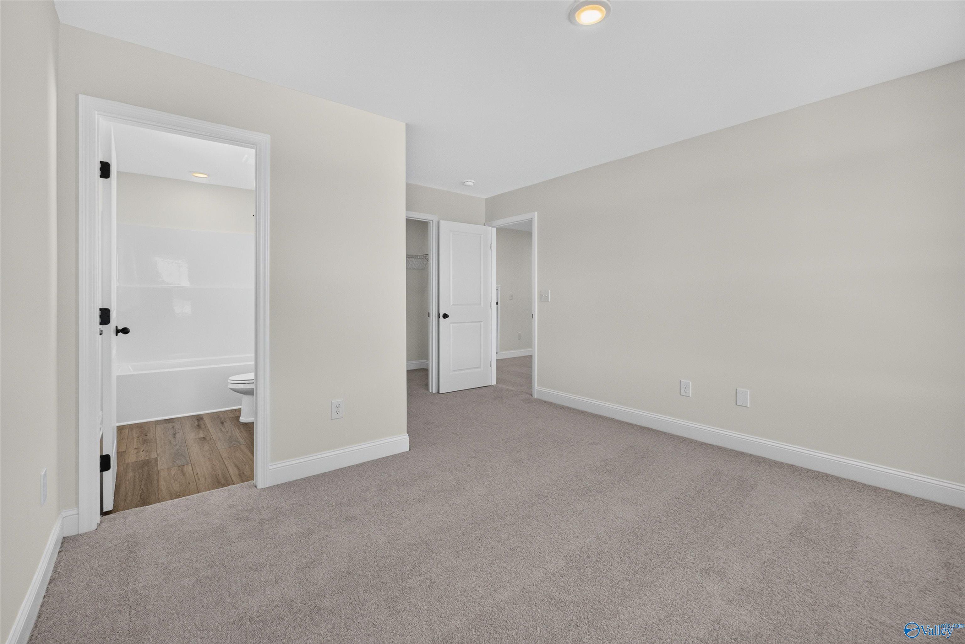 Spacious carpeted bedroom with en suite bath and walk-in closet in Davidson Homes Ashport L floor plan, Berry Cove, New Market, Alabama
