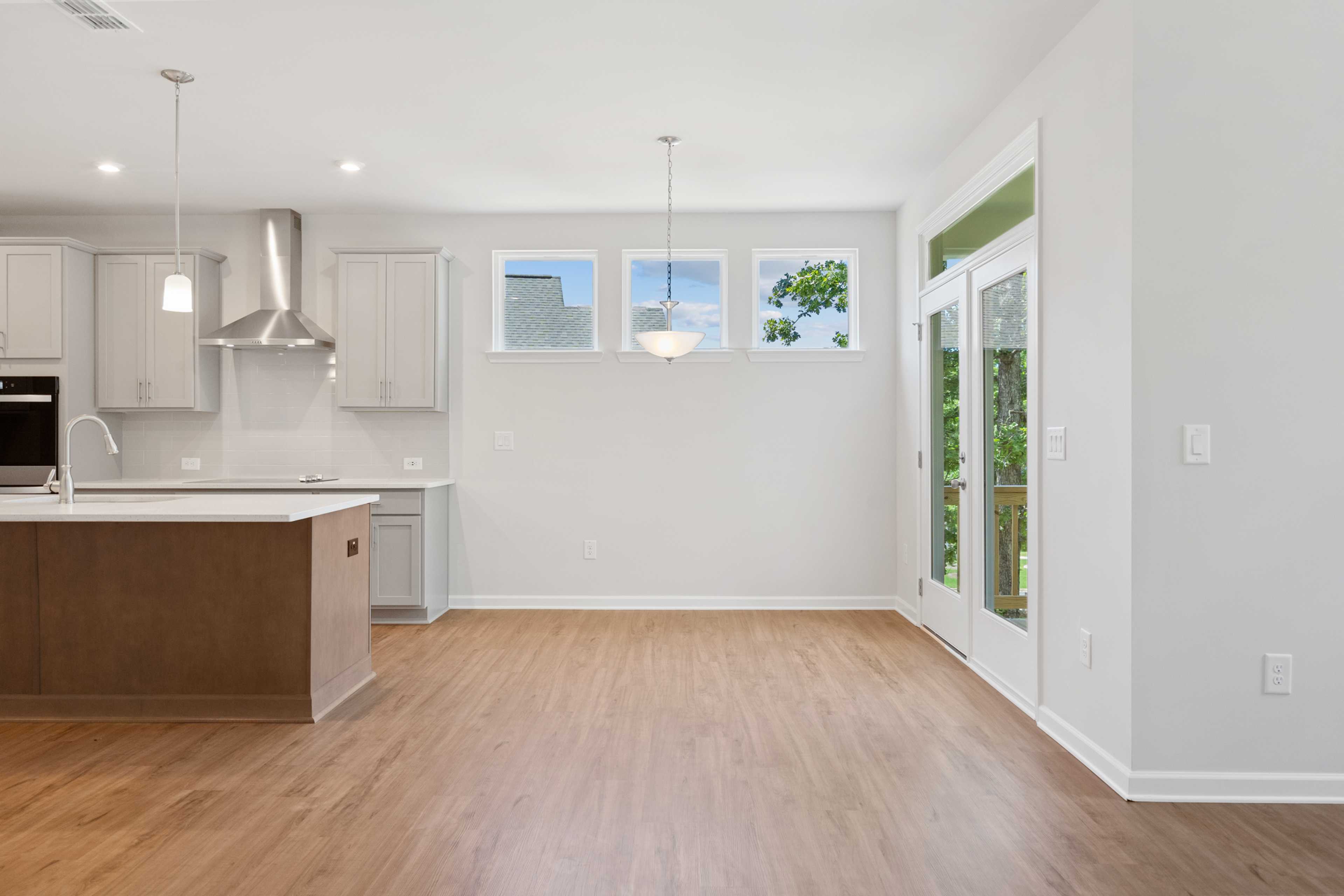 Modern open-concept kitchen at Mountainbrook in Cartersville GA with white cabinets, wood island, hardwood floors, and French doors to patio