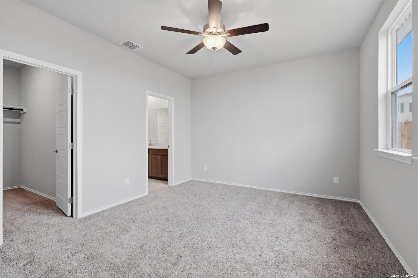 Spacious master bedroom with ceiling fan, en-suite bath, closet, and window view in Davidson Homes The Frio B, Agave, San Antonio