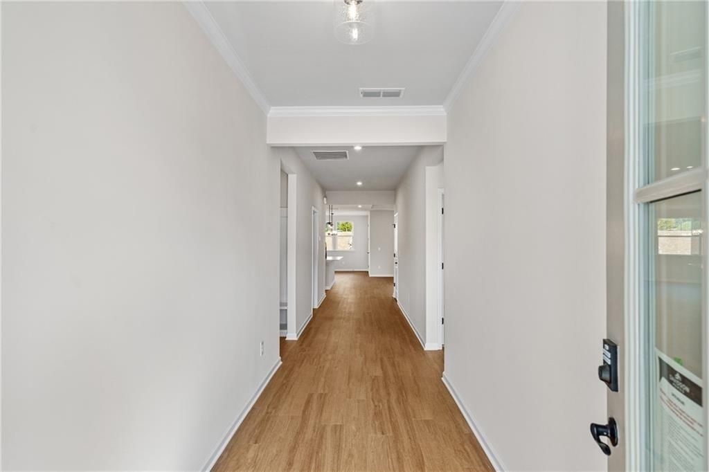 Spacious hallway with hardwood floors, white walls, and recessed lighting in Davidson Homes The Edison B, Loganville, GA