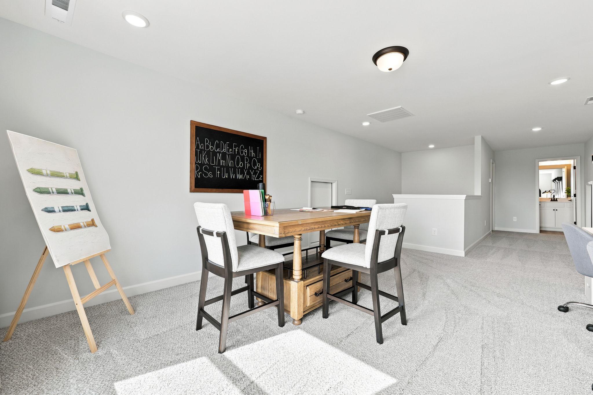 Spacious home office or playroom at Montrose in Aberdeen, NC by Davidson Homes featuring a study table and chalkboard decor.