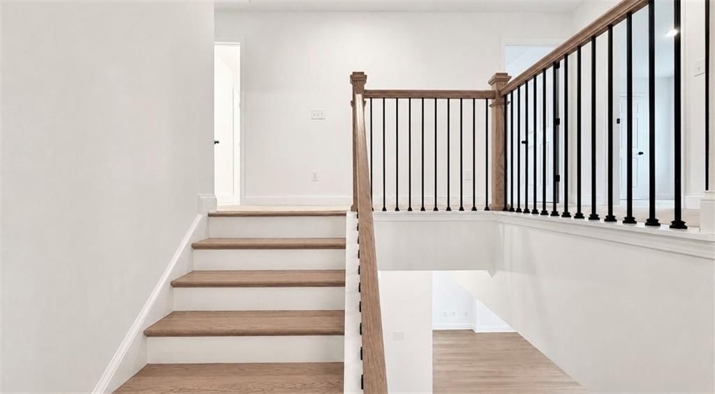 Modern staircase with oak treads and black metal railings in The Hickory C floor plan at Wehunt Meadows, Hoschton, GA.