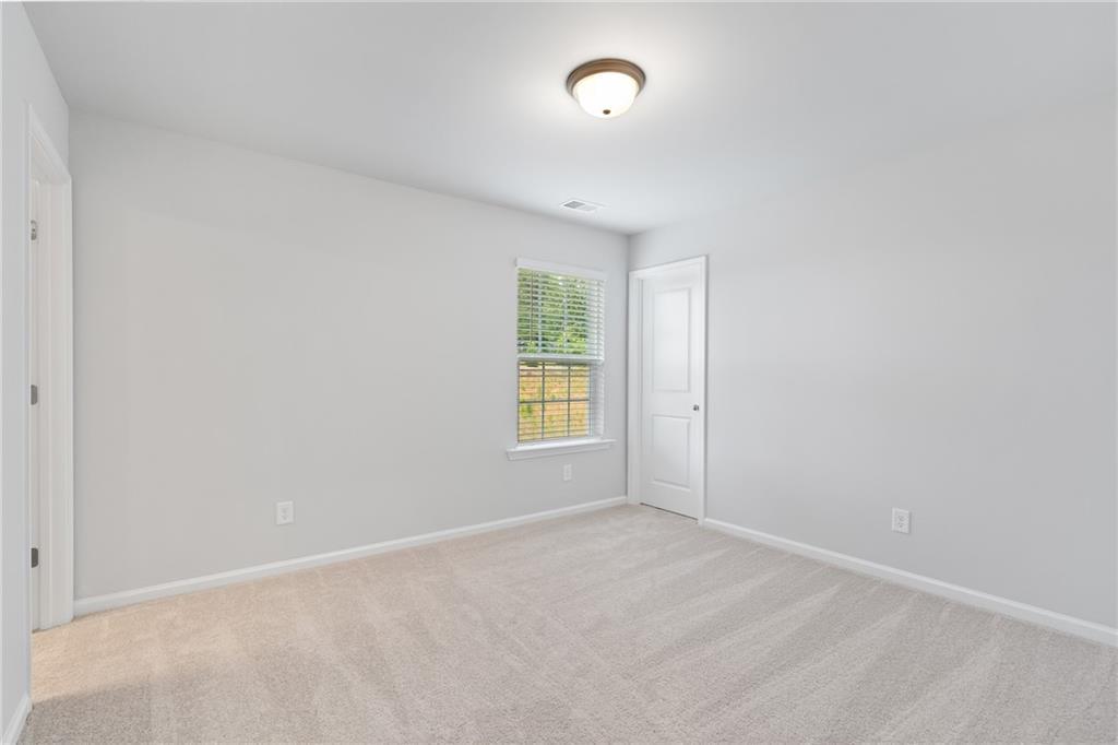 Bright empty bedroom with neutral walls, carpet floor, window blinds in Davidson Homes Hickory A, Winder, Georgia