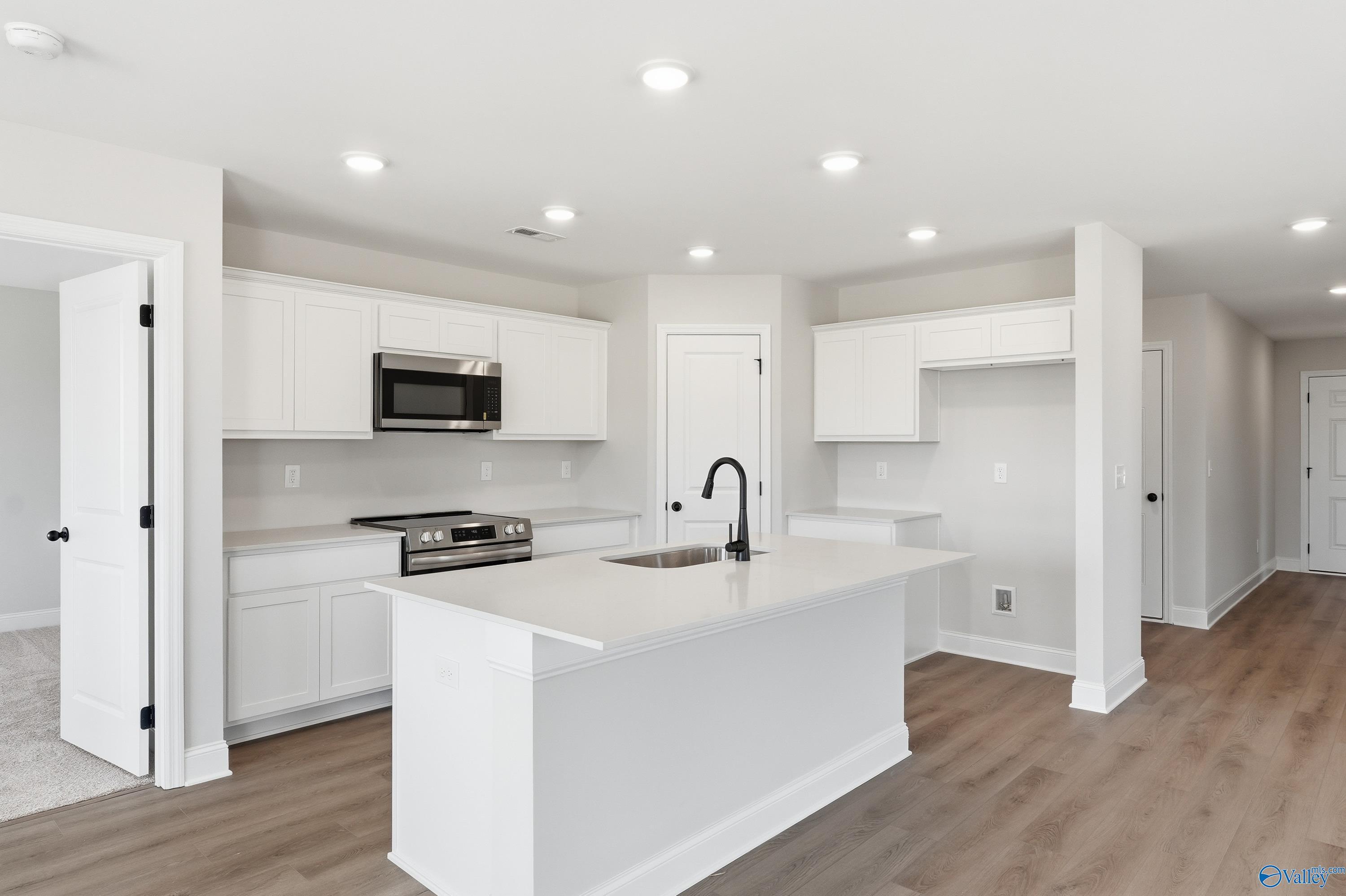 Bright modern kitchen with white cabinets, stainless appliances, and large island sink in Davidson Homes Franklin V, Athens Alabama