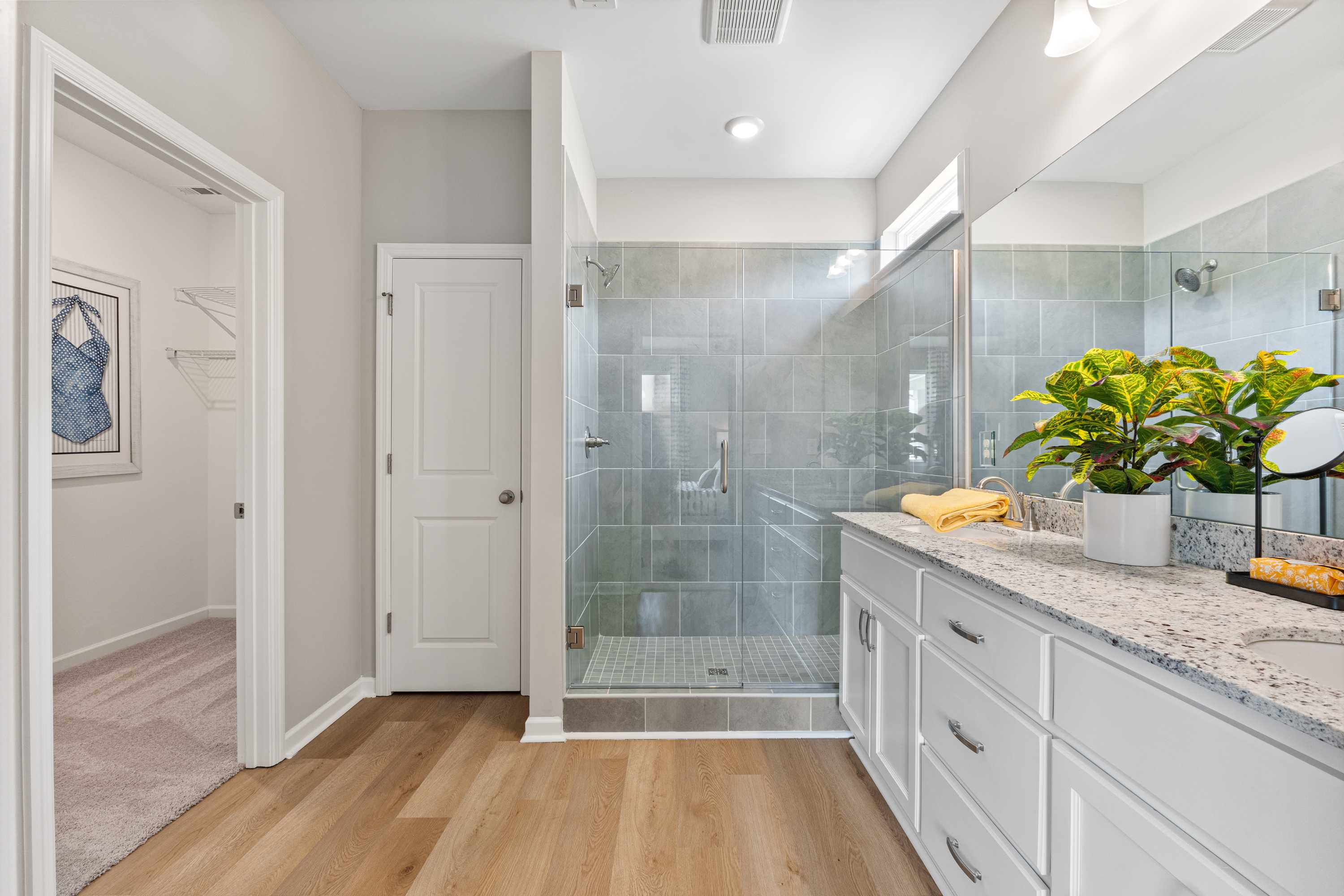 Spacious primary bathroom at Forest Glen in Hazel Green Alabama with glass walk-in shower, white double vanity, and hardwood floors