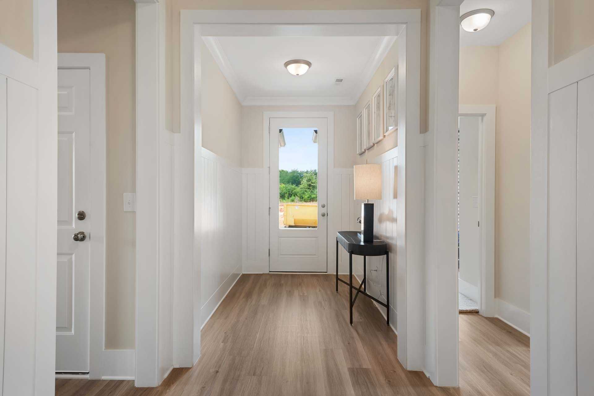 Spacious entry foyer at Flint Meadows in New Market Alabama featuring hardwood floors, console table, and scenic green view through front door